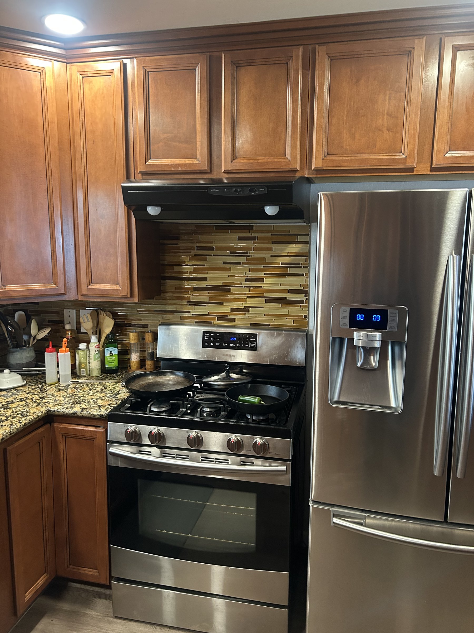 Original range hood and gold-toned tile backsplash before Phoenix remodel