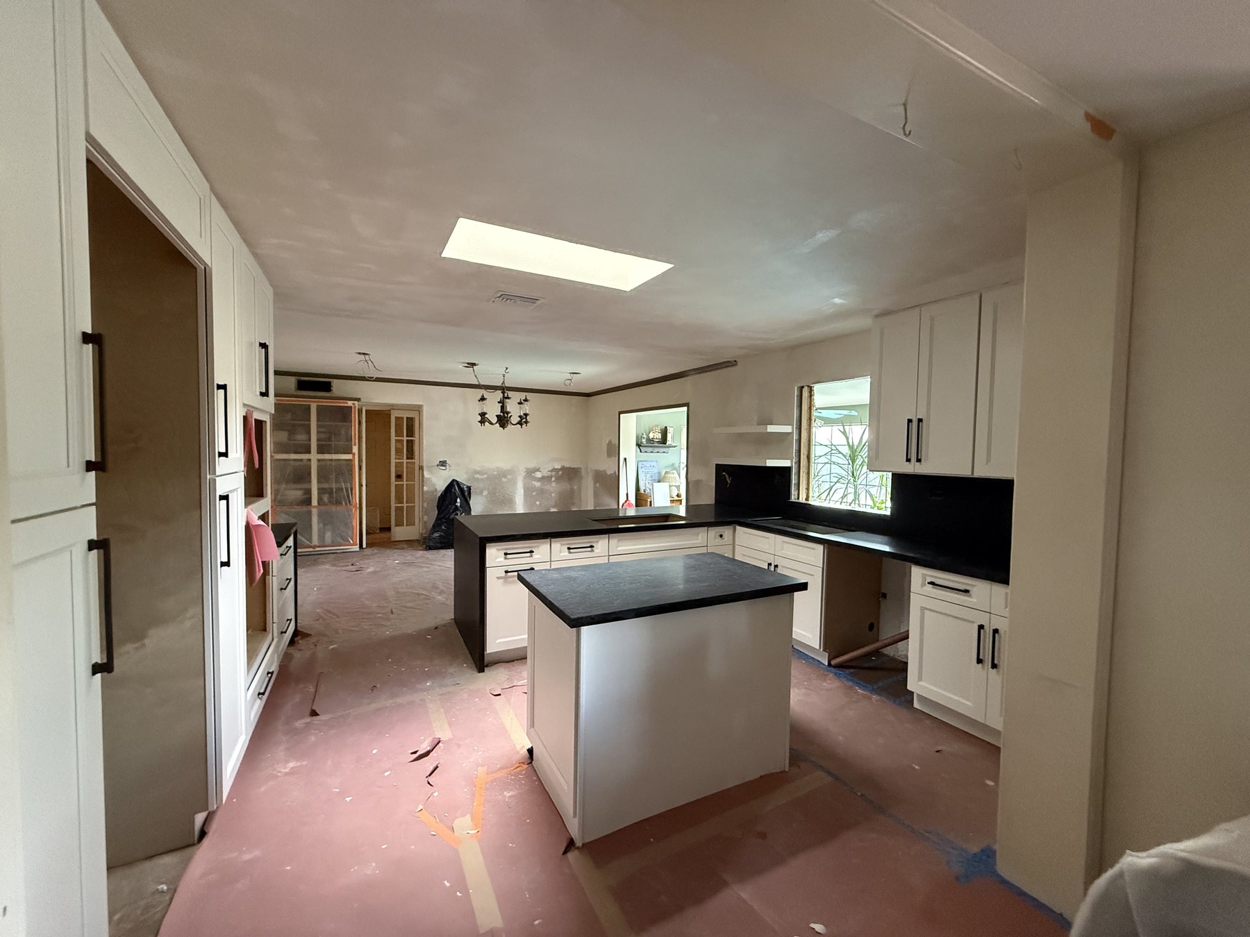 New white cabinetry and countertops installed with subfloor still exposed, Scottsdale remodel