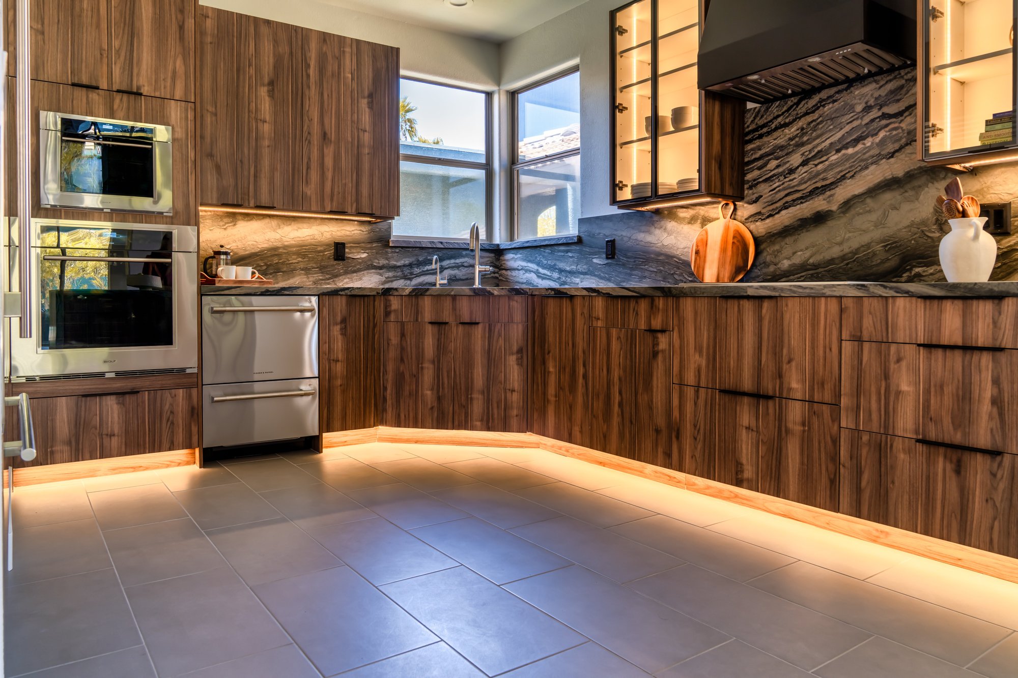 Large-format stone tile flooring with warm toe-kick lighting in a Fountain Hills kitchen remodel