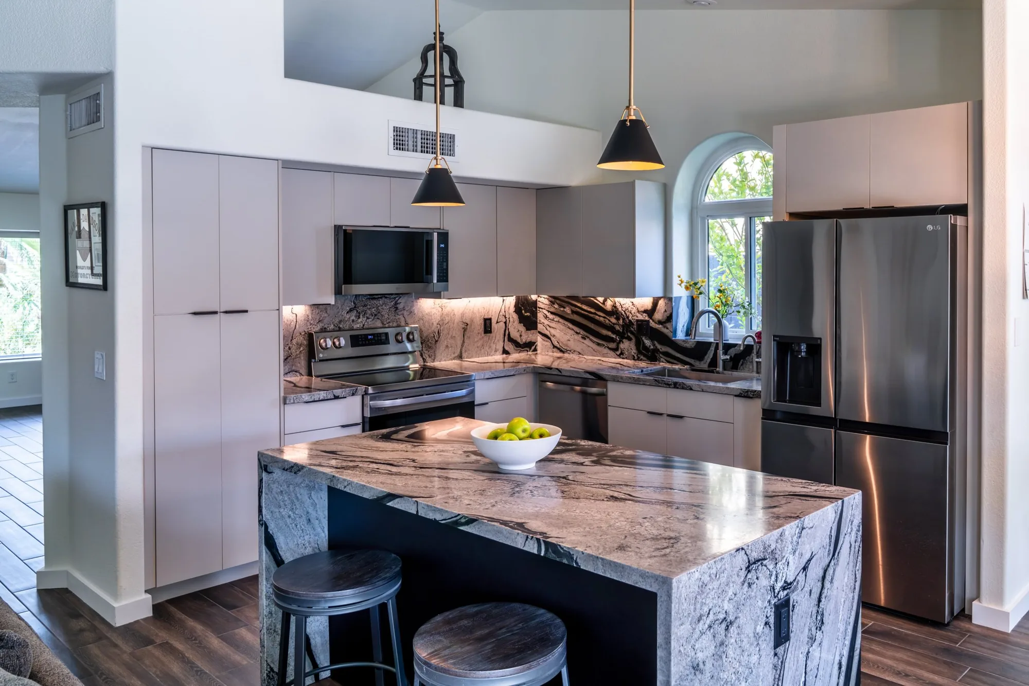 Open-concept Phoenix kitchen remodel with stone island, arched window and dining nook